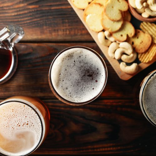 Glasses of beer and snacks on wooden table