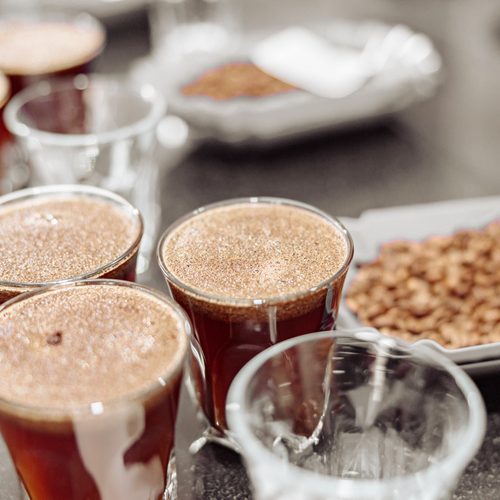 Close up of glasses of coffe and bowls with freshly roasted coffee beans for a coffee tasting